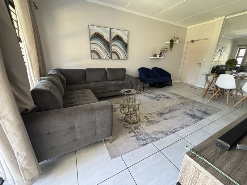 A well-maintained living room featuring neutral tiled flooring and a spacious layout, providing a comfortable and functional living area.