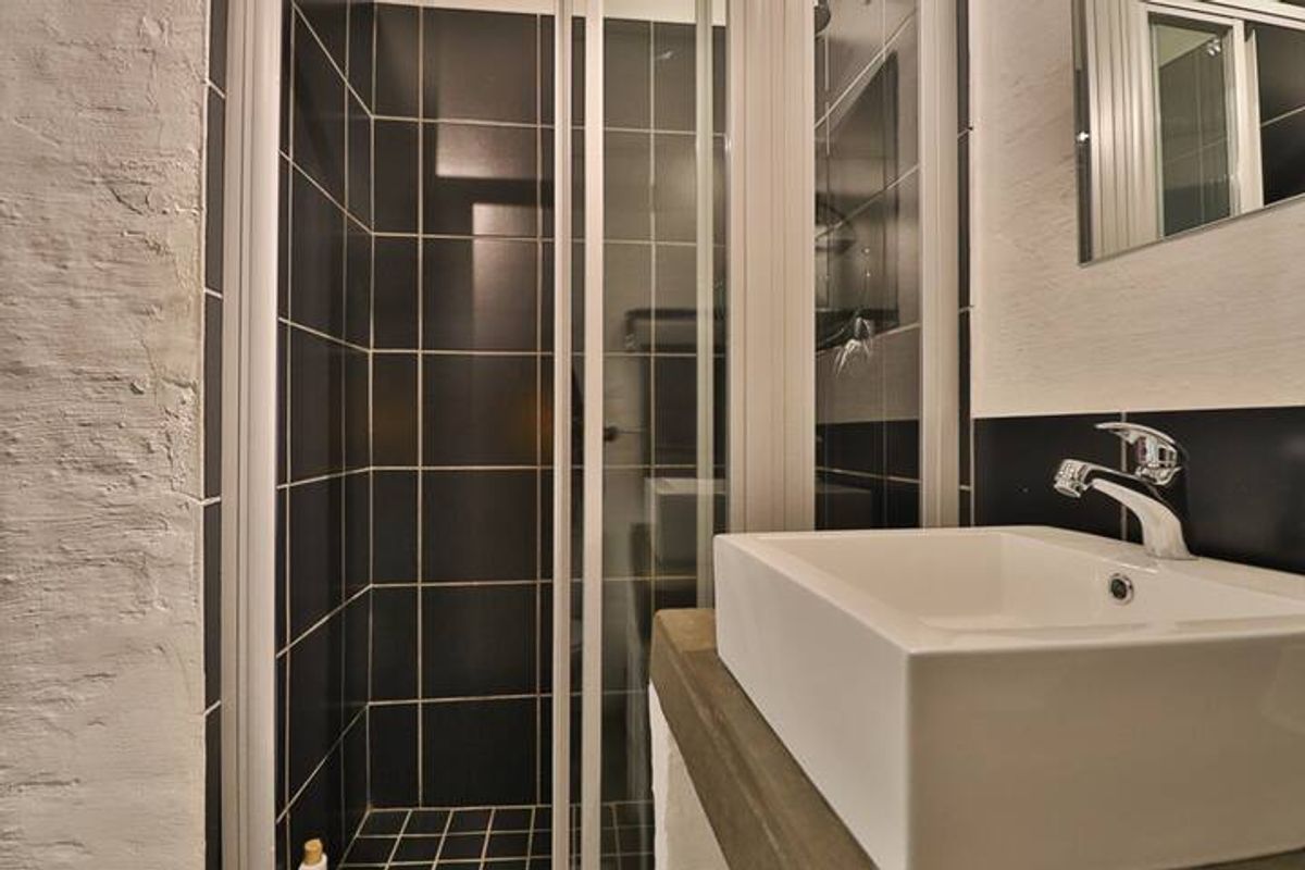A compact bathroom featuring a modern vessel sink with chrome faucet and a tiled shower enclosure with glass doors.