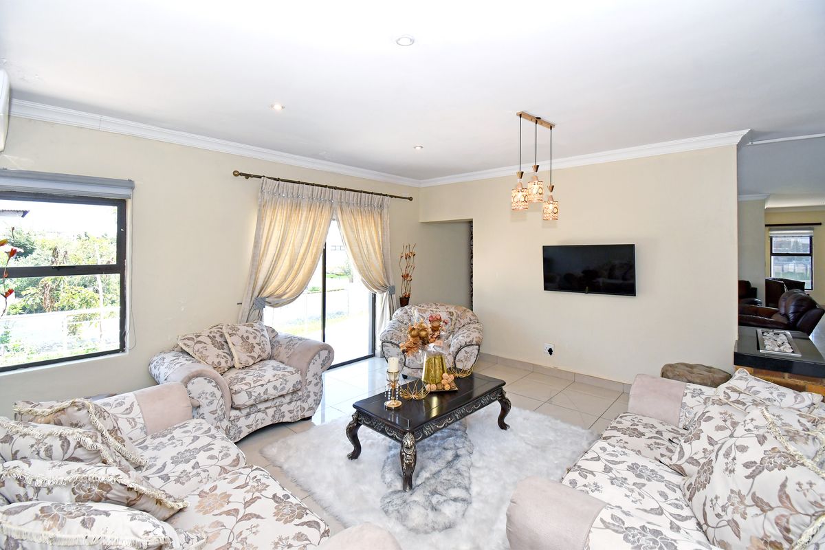 A spacious living room featuring tiled flooring, recessed ceiling lighting, and sliding glass doors that provide access to the outdoor area.