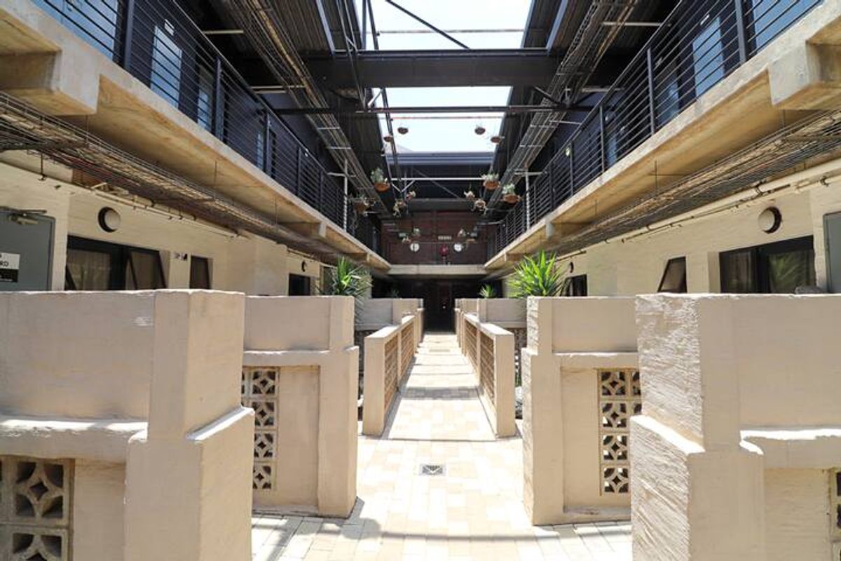 A view of the apartment complex courtyard featuring a central paved walkway, industrial-style metal railings, and exposed structural beams.