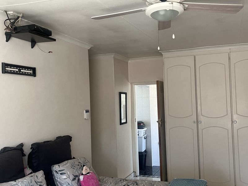 Bedroom featuring built-in cupboards, a ceiling fan, and direct access to an adjoining bathroom.