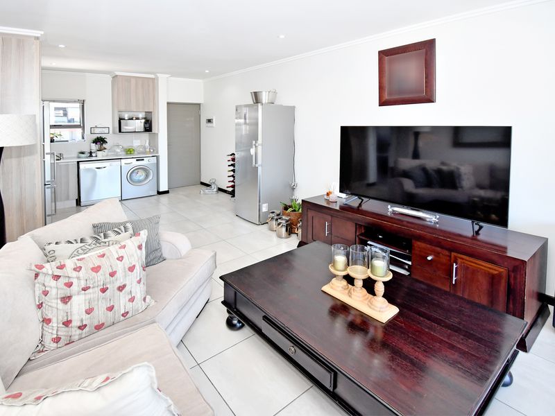 An open-plan living area featuring tiled flooring, recessed lighting, and a functional kitchen space with built-in cabinetry.