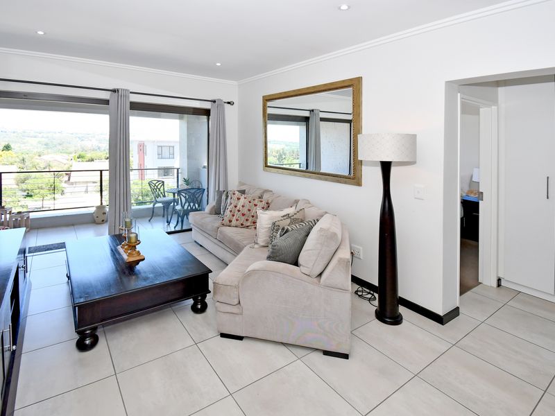 A bright living room featuring tiled floors, recessed lighting, and large sliding doors leading to a balcony, with adjacent built-in storage.