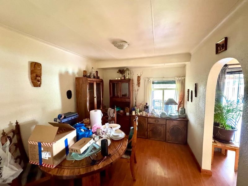 A dining room featuring laminate flooring, an arched entryway, and coved ceilings, offering a functional space ready for modernization and cosmetic updates.
