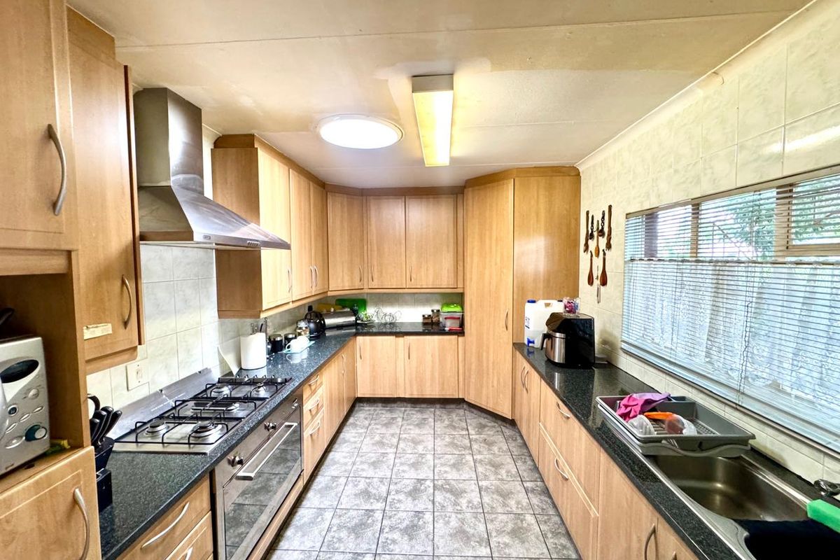 A functional kitchen featuring laminate cabinetry, granite countertops, a gas hob, built-in oven, and tiled flooring, offering a practical layout for daily meal preparation.