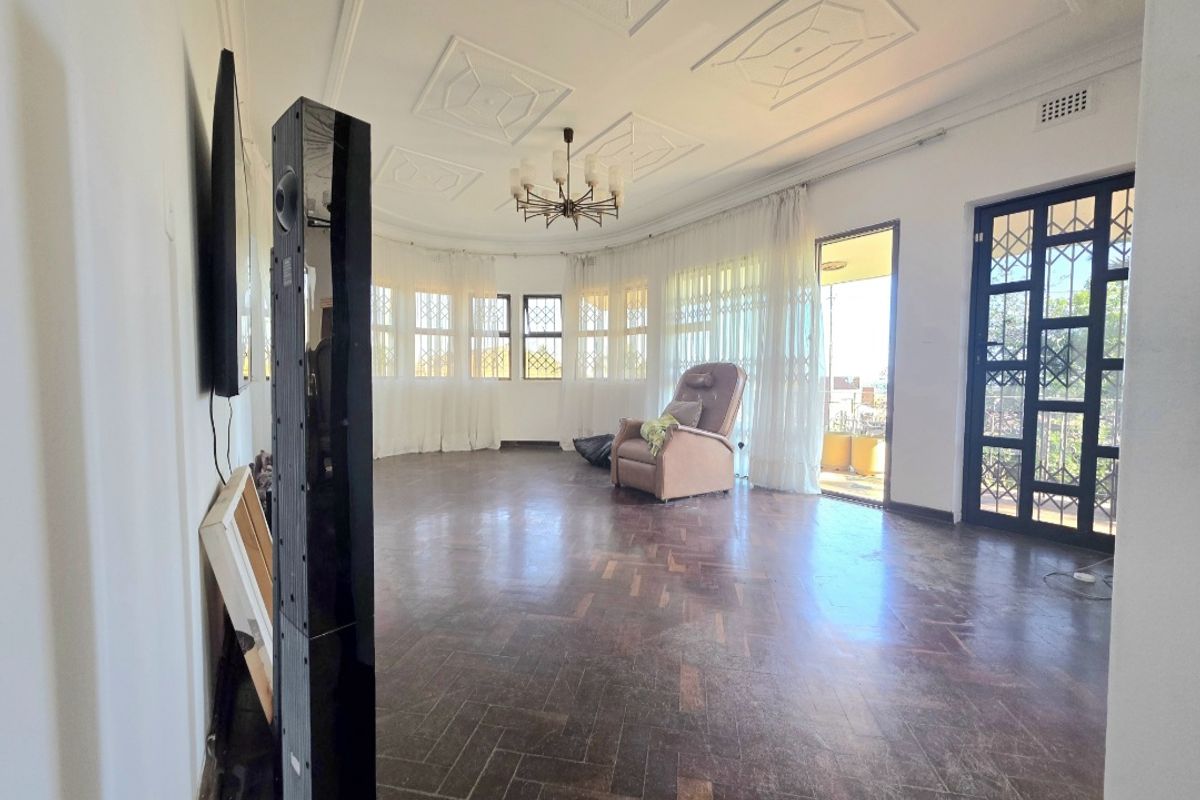 Spacious living room featuring classic herringbone parquet flooring, decorative ceiling detailing, and direct access to an outdoor patio area.
