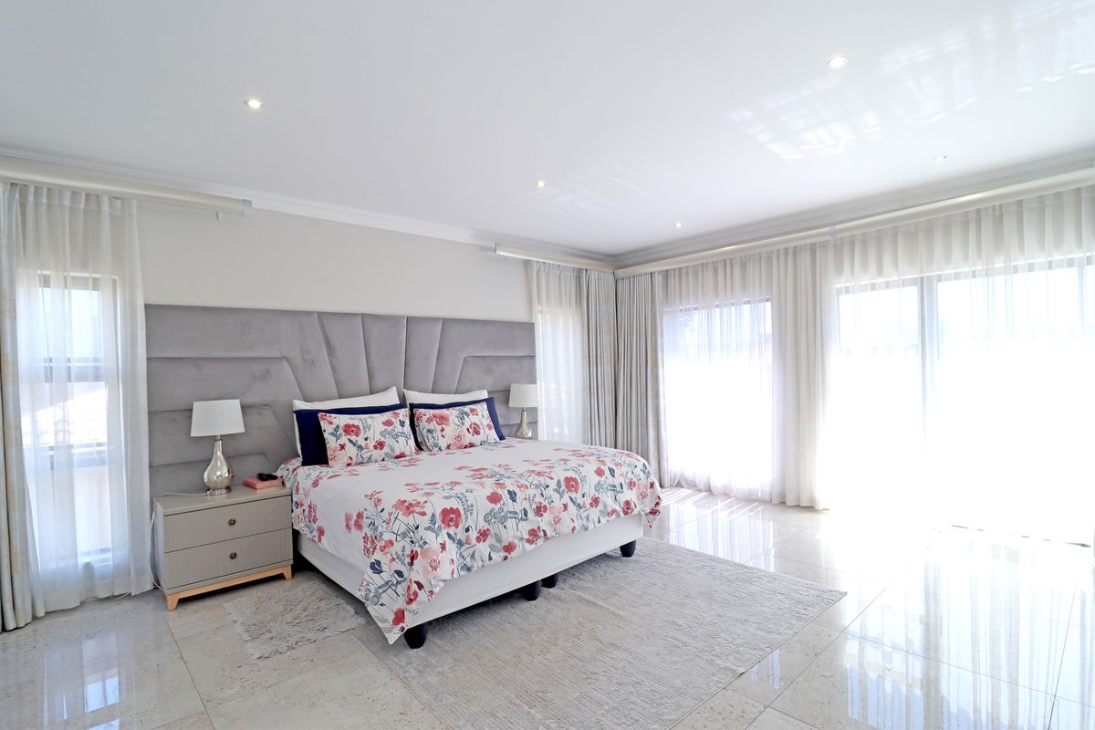 Spacious bedroom featuring polished porcelain tile flooring, recessed downlighting, and large sliding glass doors with integrated curtain tracks.