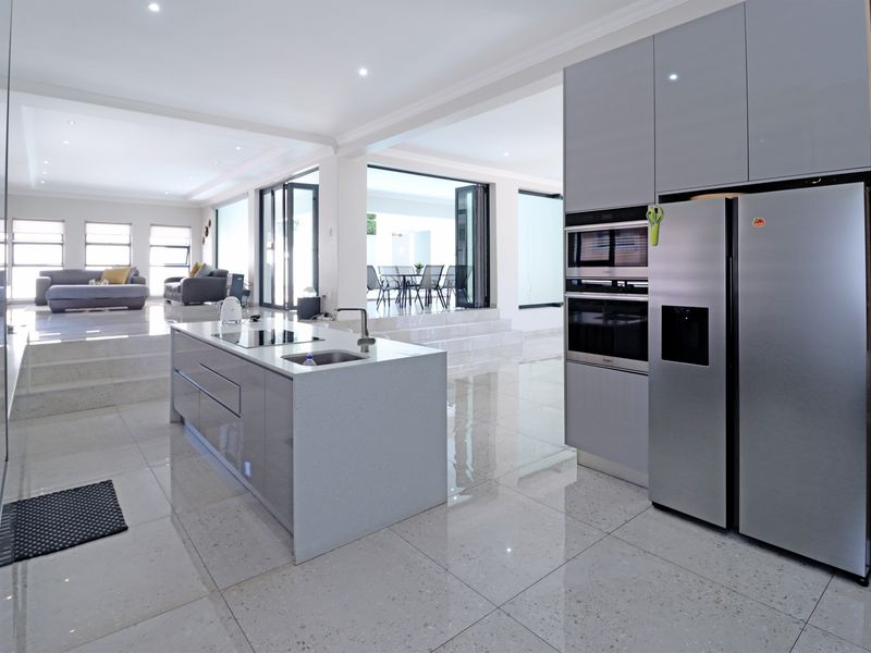 Modern open-plan kitchen featuring a central island, high-end built-in appliances, sleek cabinetry, and seamless flow to the living and dining areas.