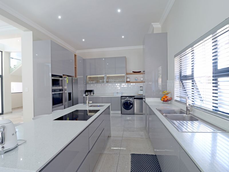 Modern kitchen featuring a large central island with induction cooktop, quartz countertops, integrated cabinetry, built-in appliances, and high-quality finishes throughout.