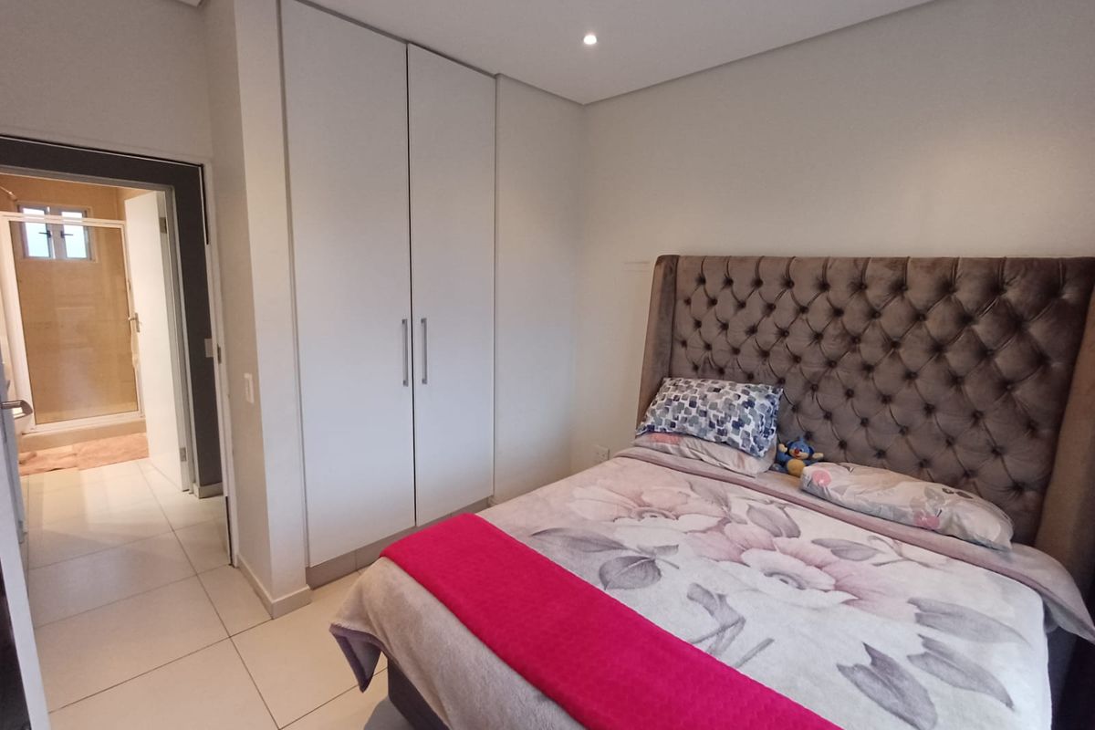 A well-maintained bedroom featuring built-in cupboards, tiled flooring, and recessed lighting, with direct access to an en-suite bathroom.