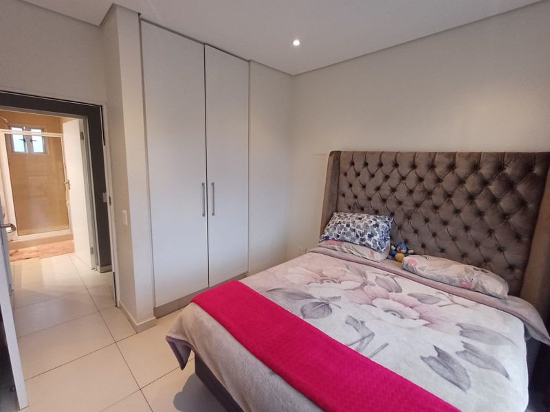 A well-maintained bedroom featuring built-in cupboards, tiled flooring, and recessed lighting, with direct access to an en-suite bathroom.