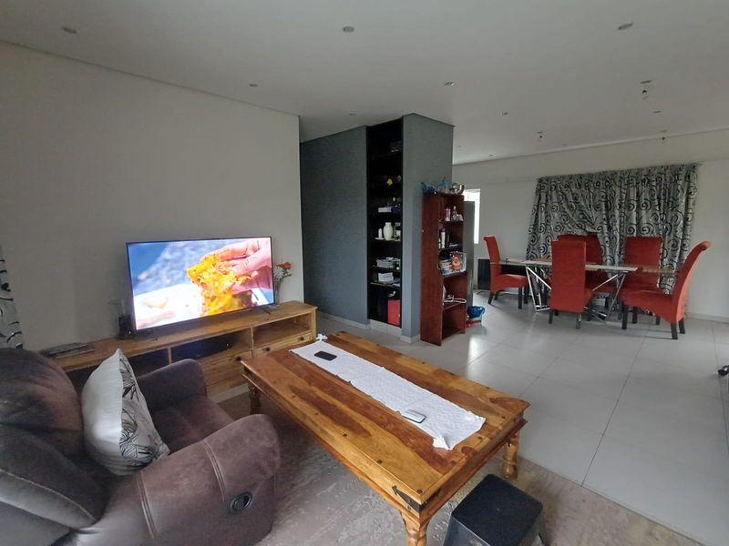 Open plan living and dining area featuring tiled flooring, recessed ceiling lighting, and a built-in shelving unit.