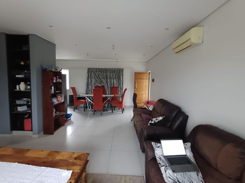 Spacious open-plan living and dining area featuring tiled flooring, recessed lighting, and a wall-mounted air conditioning unit.