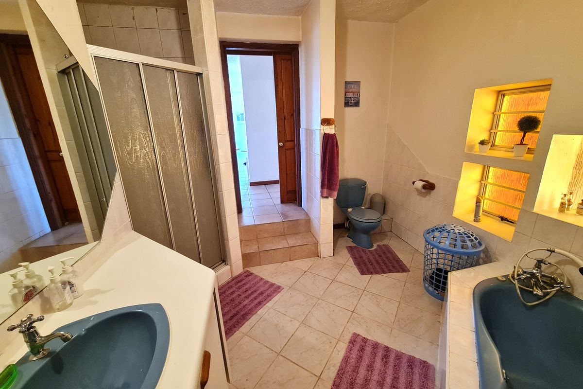 A dated bathroom featuring a blue suite, including a built-in bathtub, shower enclosure, and vanity basin with recessed wall shelving.