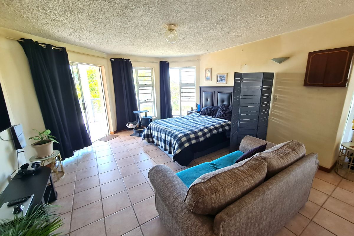 Spacious bedroom featuring tiled flooring, textured ceiling, and direct access to an outdoor area through sliding glass doors.