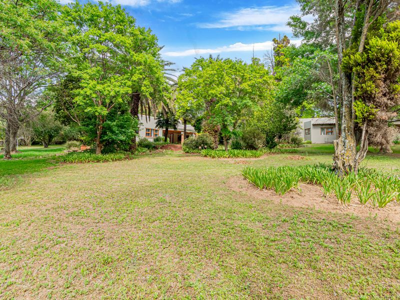 A spacious, well-maintained garden area featuring mature trees, established landscaping, and expansive lawn space surrounding the property.