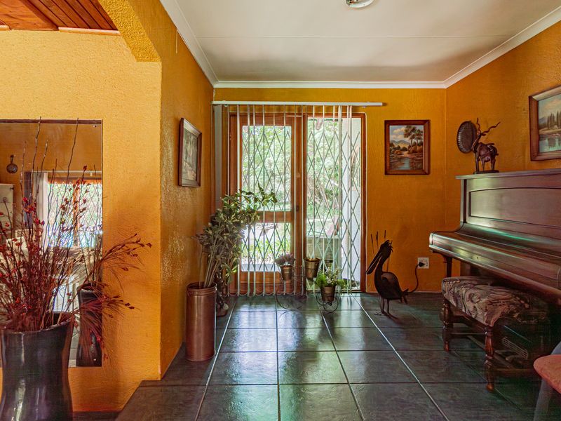 Entrance hall featuring dark tiled flooring, textured walls, and a glass sliding door with a security gate leading to the exterior.