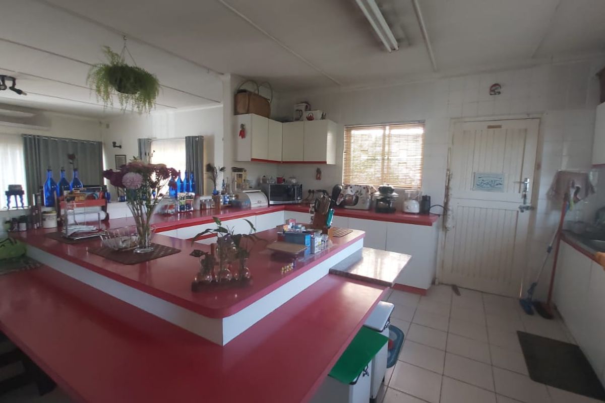 A spacious kitchen featuring extensive built-in cabinetry, a large central island with laminate countertops, and tiled flooring, offering significant potential for modern renovation.