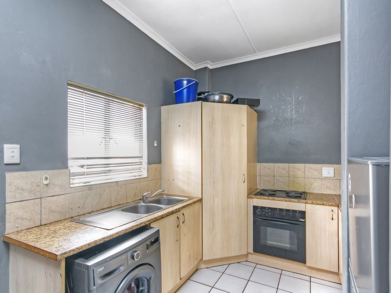 Compact kitchen featuring built-in cabinetry, laminate countertops, a stainless steel sink, and a built-in oven with an electric hob.