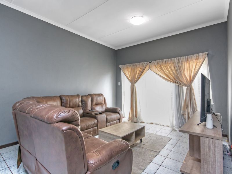A comfortable living room featuring tiled flooring and a sliding glass door that provides natural light and access to the outdoor area.