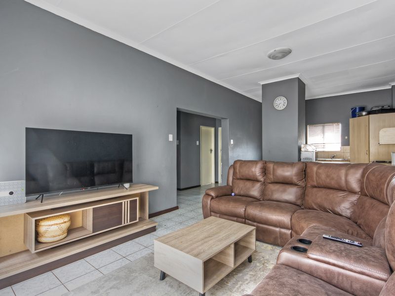 Open-plan living area featuring tiled flooring and an integrated kitchen space with built-in cabinetry and sink.