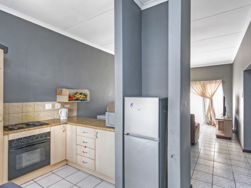 Open-plan kitchen and living area featuring tiled floors, granite countertops, built-in oven, and hob, with a neutral grey color scheme.