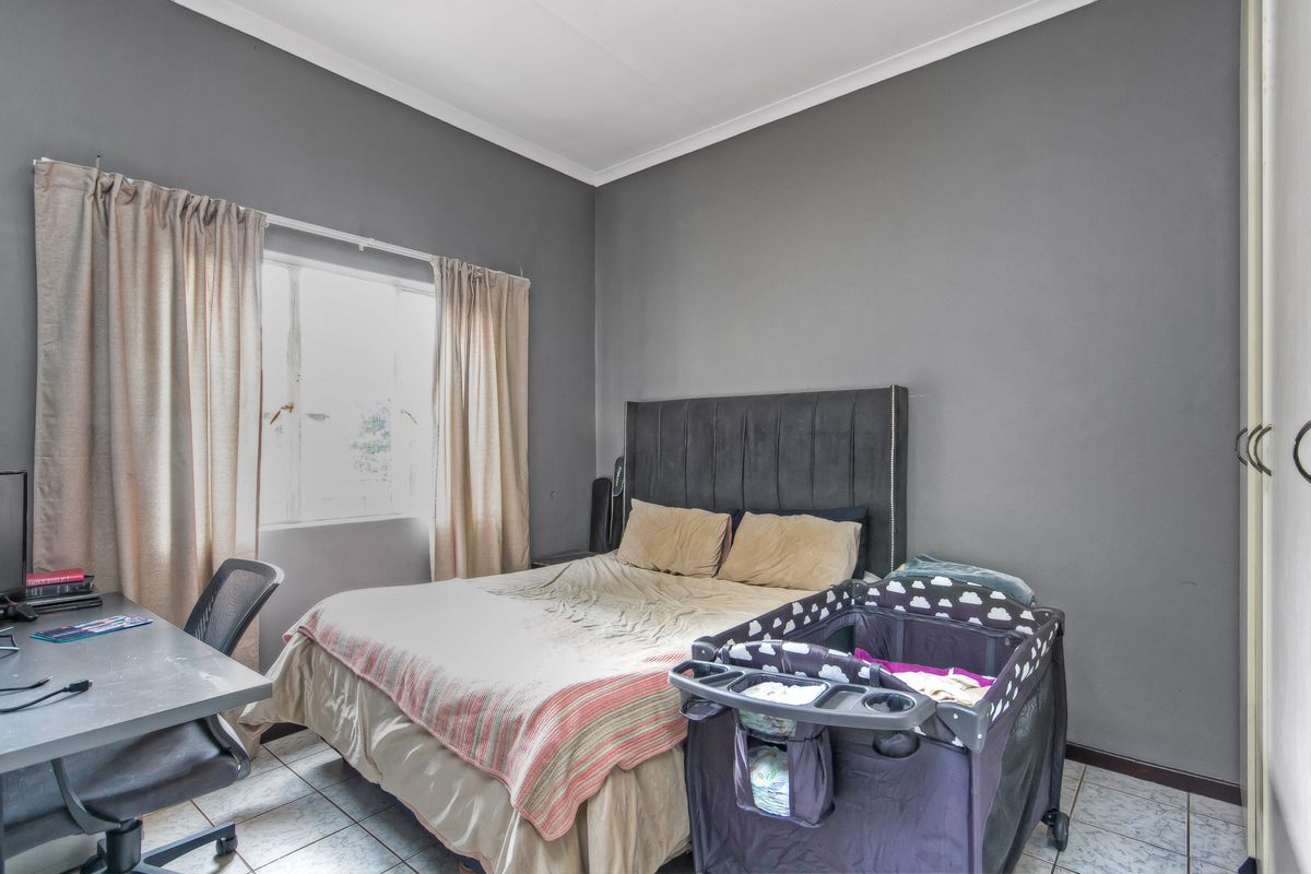 A bedroom featuring tiled flooring, coved ceilings, and a built-in wardrobe, providing a functional space with neutral grey wall finishes.