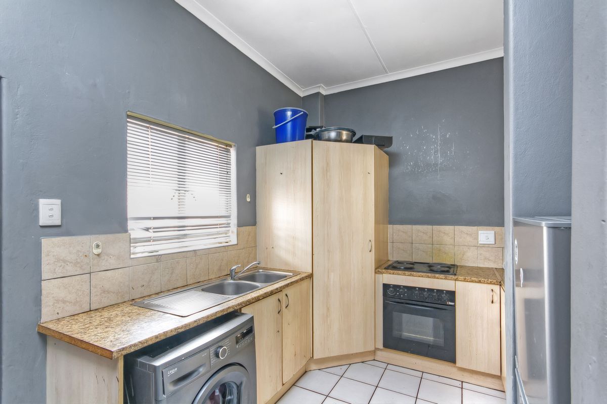 Compact kitchen featuring built-in cabinetry, laminate countertops, a stainless steel sink, and a built-in oven with an electric hob.