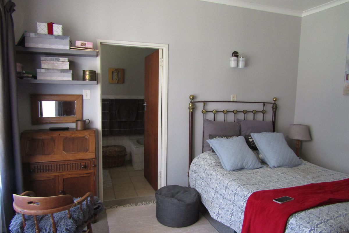 A bedroom featuring neutral wall tones, wall-mounted shelving, and direct access to an en-suite bathroom.
