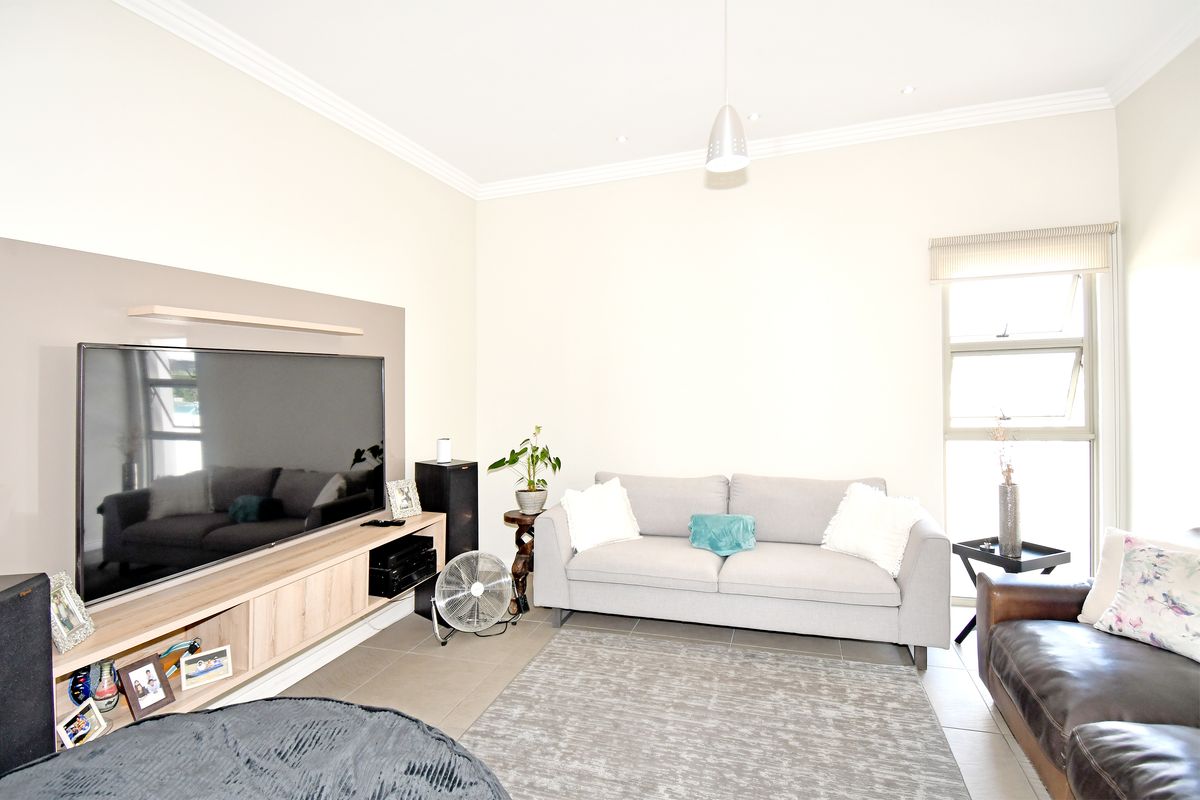 A bright living room featuring tiled flooring, recessed ceiling lighting, crown molding, and a built-in media console unit.