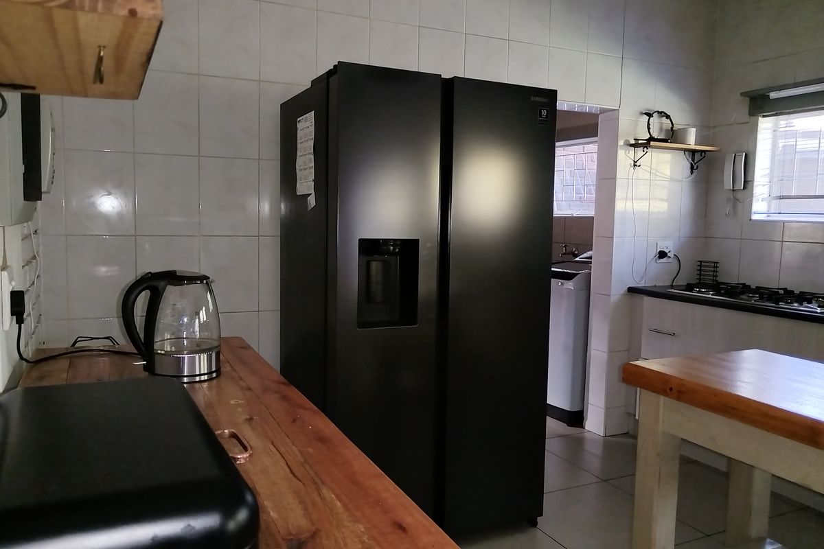 A functional kitchen featuring tiled splashbacks, timber countertops, and a built-in gas hob, with an adjacent scullery area visible.