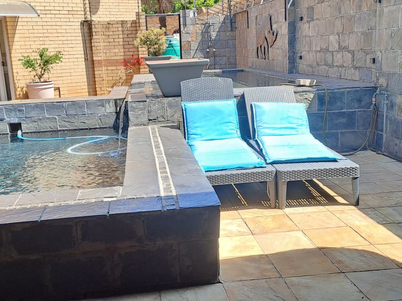 Outdoor pool area featuring a built-in swimming pool, stone-clad walls, and paved patio space, ideal for relaxation and outdoor entertainment.