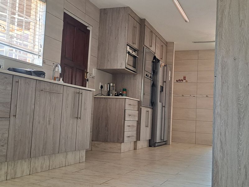 A modern kitchen featuring light wood-grain cabinetry, built-in oven and microwave, tiled flooring, and a tiled backsplash.