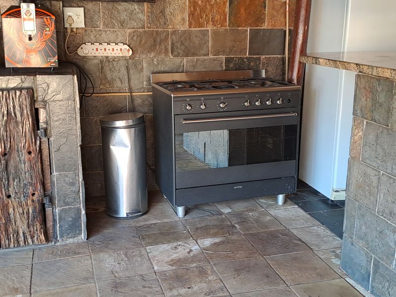 A rustic kitchen area featuring stone tile wall cladding, granite countertops, and a built-in gas stove with oven.