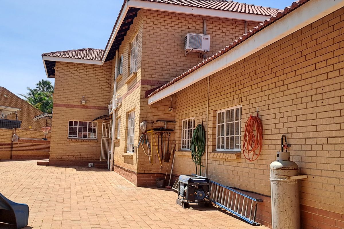A spacious rear courtyard featuring face brick exterior walls, paved flooring, and secure window treatments, providing a functional outdoor utility area.