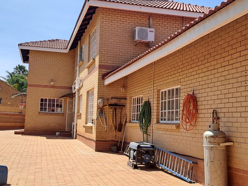 A spacious rear courtyard featuring face brick exterior walls, paved flooring, and secure window treatments, providing a functional outdoor utility area.