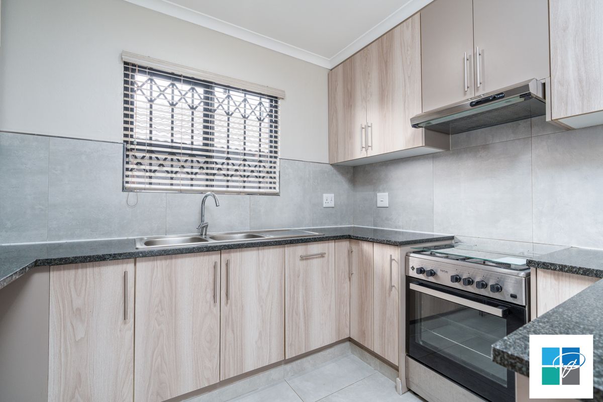 Modern kitchen featuring light wood-grain cabinetry, granite countertops, a stainless steel double sink, and a built-in gas stove with an extractor fan.