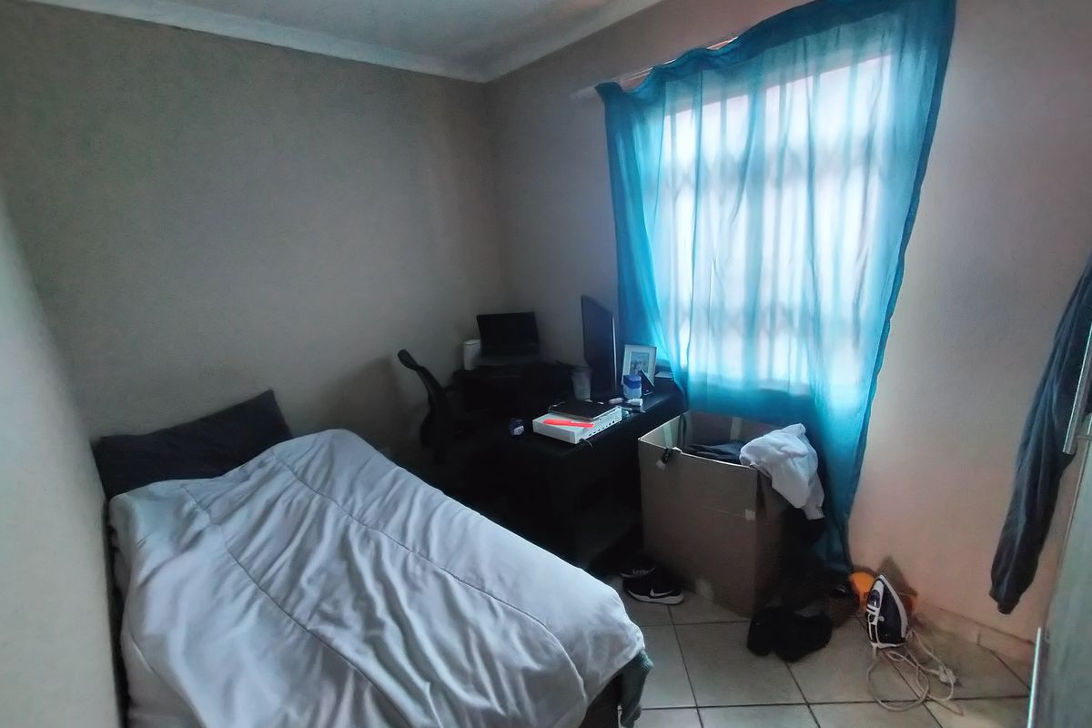A functional bedroom featuring tiled flooring and coved ceiling details, offering a neutral base for potential interior updates.