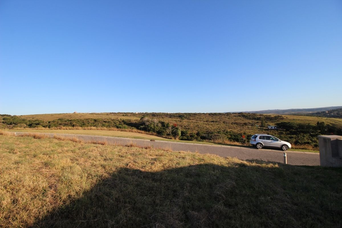 A wide-angle view of the natural landscape and surrounding terrain, featuring a paved road and open grassy areas.