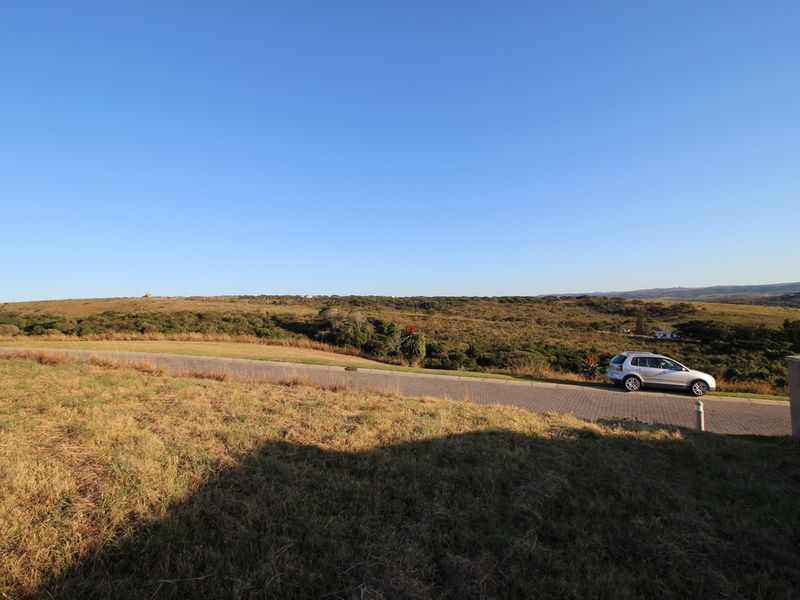 A wide-angle view of the natural landscape and surrounding terrain, featuring a paved road and open grassy areas.