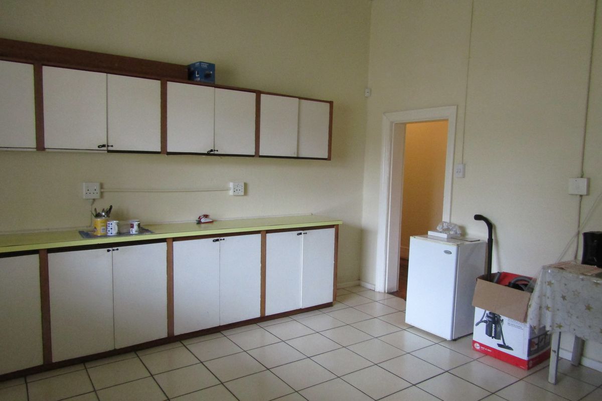 A functional kitchen or utility space featuring white cabinetry, laminate countertops, and tiled flooring, providing ample storage and workspace.