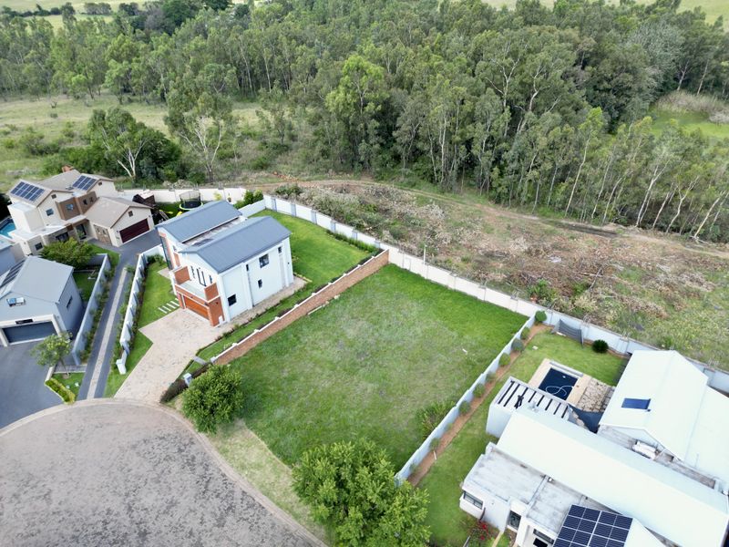 Aerial view of a residential vacant plot situated within a developed estate, featuring established boundary walls and surrounding landscaped properties.