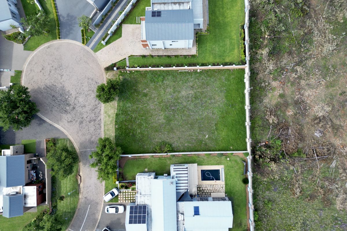 Aerial view of a vacant residential plot situated within a developed estate, featuring established boundary walls and surrounding landscaped grounds.