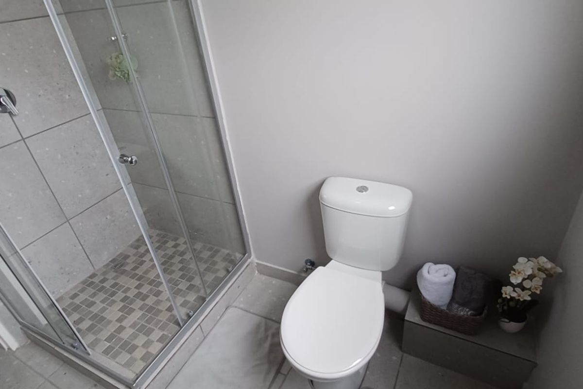 A functional bathroom featuring a glass-enclosed shower with tiled walls and a standard white toilet.