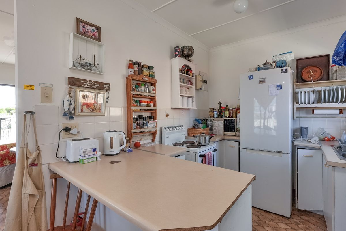 A functional kitchen featuring laminate countertops, a tiled splashback, and a freestanding electric stove, offering potential for modernization and aesthetic updates.