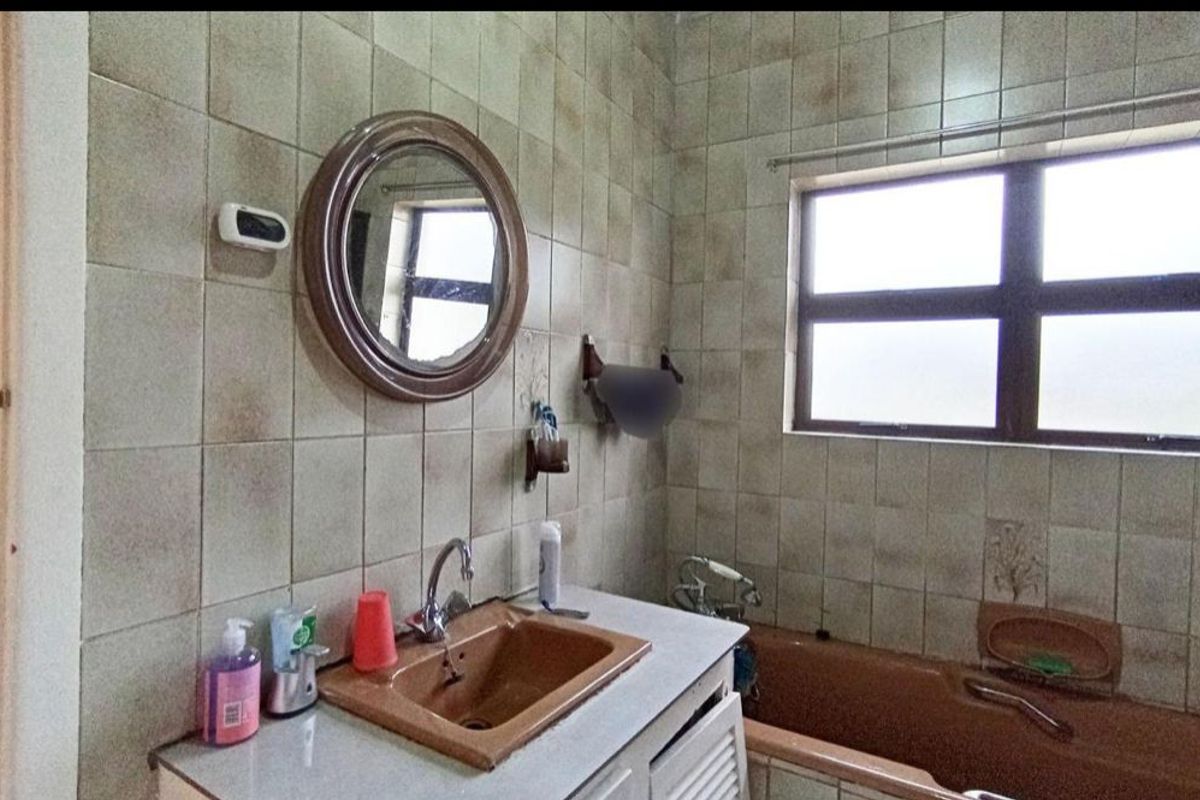 A dated bathroom featuring a built-in vanity with an integrated sink, a bathtub, and tiled walls, offering potential for a modern renovation.