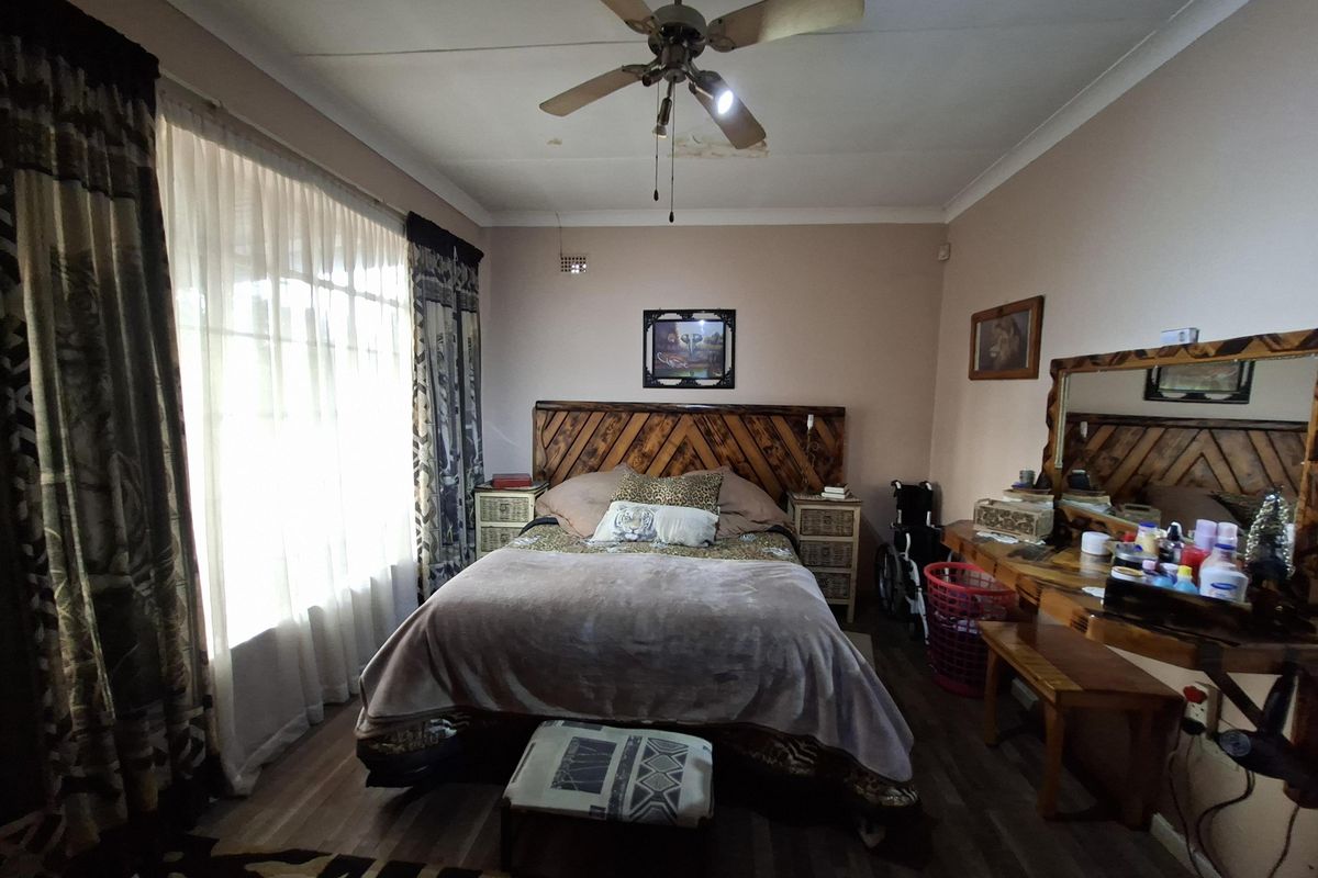 A bedroom featuring laminate flooring and a ceiling fan, showing signs of ceiling water damage.