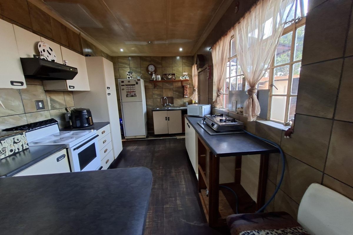 A functional kitchen featuring built-in cabinetry, tiled wall finishes, and a double sink, offering a practical layout with potential for modern cosmetic updates.
