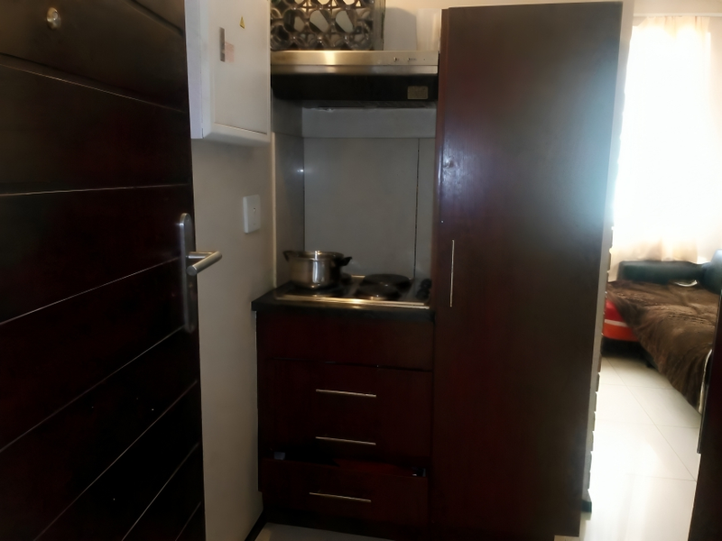 Compact kitchen area featuring dark wood cabinetry, a built-in hob, and an extractor fan, situated adjacent to the main living space.