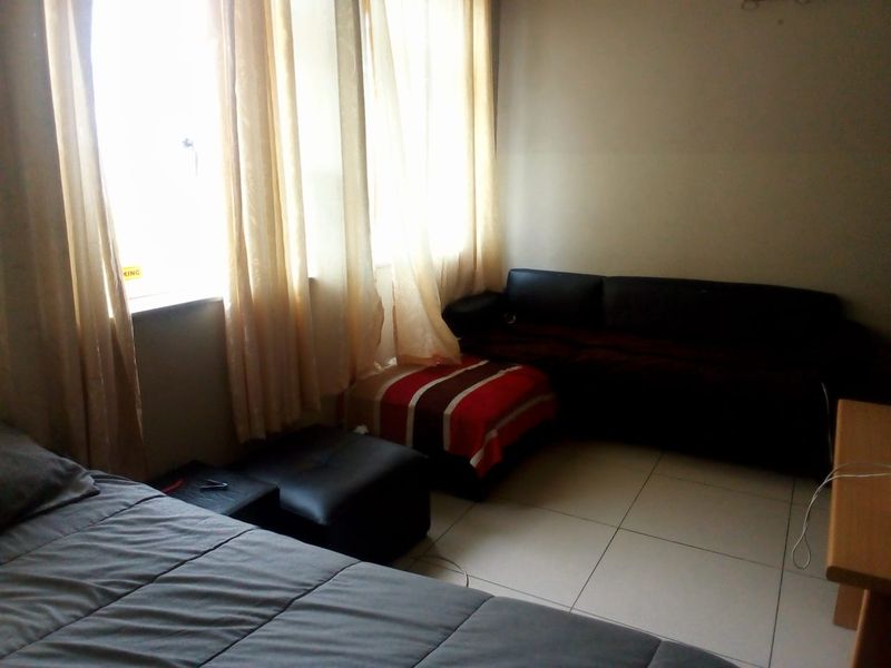 A bedroom featuring tiled flooring and large windows that allow for natural light.